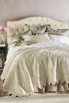 the bed is made with white linens and has a flower arrangement on top of it