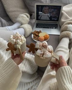 two people holding hot dogs and marshmallows in front of a laptop