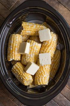 corn on the cob with butter and cheese in an air fryer bowl, ready to be cooked