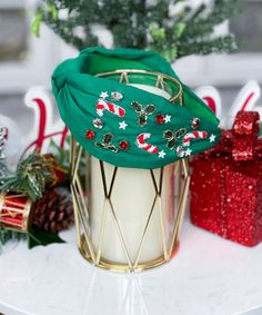 a green christmas hat sitting on top of a white table next to red and silver presents