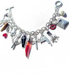 Vampire slayer bracelet has all the accoutrements needed to accomplish the task.  Great assortment of charms include:  A FANG SHAPED GLASS VIAL filled with a Blood Red liquid - Actually a candied syrup. Vial measures 1 & 1/4 inches long. DOUBLE NAILED CROSS - measures 1 inch long BAT WING CHARM  BLACK ENAMELED COFFIN CHARM with ETCHED CROSS measures 1 inch long. BOW & ARROW charm measures 1 inch long SKELETON HAND SPIDER CHARM topped with Black crystal measures 1 " BAT CHARM with tiny Black crystal  SKULL HEAD measures 3/4 inches FANG charm with a faceted Blood Red Crystal charm measures 1 & 1/2 inches long WOODEN STAKE charm is made out of genuine bone and measures 1 inch long RIP TOMBSTONE CHARM WITH OVERLAID BAT measures 1.3 inches long RED & BLACK ENAMELED FANG charm Tiny GARLIC BULB c Rip Tombstone, Wooden Stake, Red Liquid, Long Bow, Bow Arrow, Garlic Bulb, Bow Arrows, Bat Wing, Glass Vials