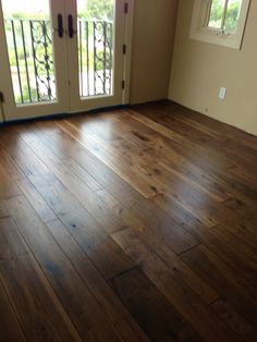 an empty room with wooden floors and french doors