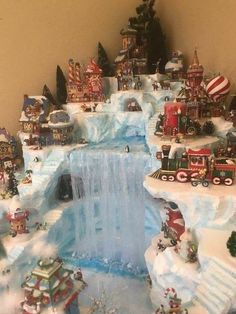 a christmas village with train tracks, trees and buildings on top of snow covered ground