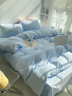 an unmade bed with blue sheets and pillows on top of it in a bedroom