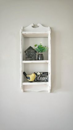 a white shelf with two vases on top of it and a bird figurine next to it