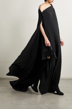 Balenciaga's gown features a dramatic cape-effect back that drapes down to the floor and leaves a short train. Made from crepe, it has an asymmetric neckline and frayed edges for a purposely undone feel. Wear yours with sock boots and one of the label's totes. Evening Gown With Cape Sleeves And Pre-draped Style, Pre-draped Cape Evening Dress, Evening Gown With Long Train, Evening Maxi Dress With Sweep Train And Cape Sleeves, Chic Evening Gown With Cape Sleeves, Luxury Cape Evening Dress, Cape Evening Dress With Sweep Train, Evening Dress With Cape Shape And Pre-draped Style, Evening Maxi Dress With Cape Sleeves