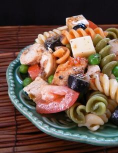 a pasta salad with meat and vegetables on a green plate