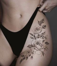 a woman's stomach with flowers and leaves tattooed on the side of her body