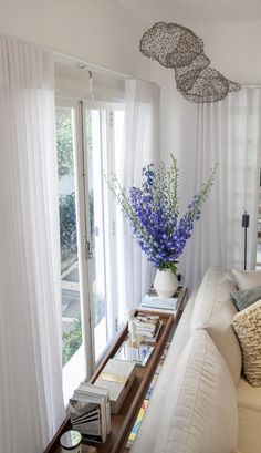 a living room filled with furniture and a large window covered in white drapes next to a wooden coffee table