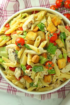 a white bowl filled with pasta salad on top of a red and white checkered table cloth