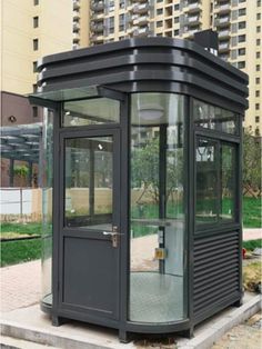 a small black and gray bus stop on the side of the road with buildings in the background