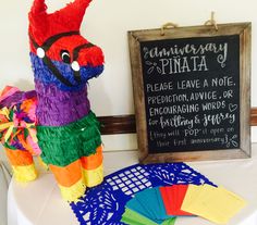 a colorful pinata sitting on top of a table next to a chalkboard sign