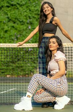 two young women are posing on the tennis court