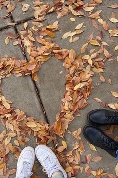 two people standing on the ground with their feet up in front of them, surrounded by leaves