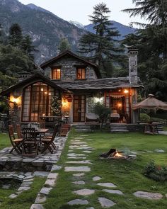 a stone path leading to a house with lights on the windows and patio furniture in front of it