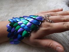 a woman's hand wearing a multicolored bracelet with chains on the wrist