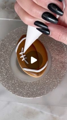 a woman's hand is sprinkling icing on a decorated cookie