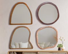 three mirrors mounted on the wall above a dresser with bookshelves and vases