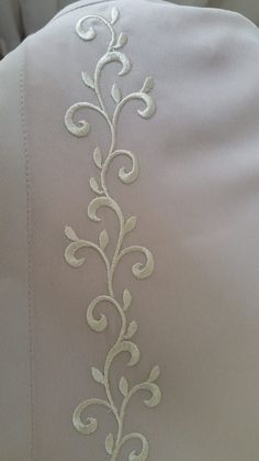 the back of a white shirt with an embroidered design on it