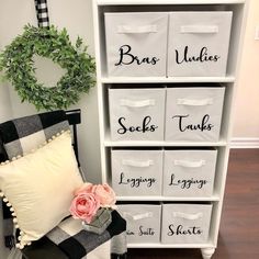 a white bookcase filled with lots of storage bins next to a pink flower