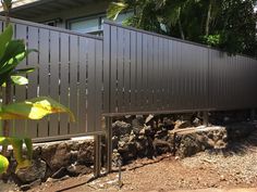 a fence that is in front of a house with rocks on the ground next to it