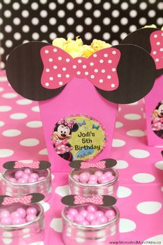 a minnie mouse birthday party with pink and white polka dot tablecloth, cupcakes and candy