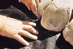 a person cutting something on top of a piece of cloth next to some rock formations