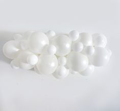 white balloons are arranged in a row on the wall