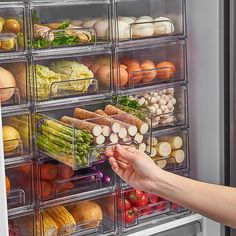 a person reaching into an open refrigerator filled with lots of vegetables and fruits, including asparagus