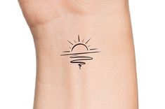 a small sun tattoo on the wrist is shown in black ink, and it appears to be drawn by hand