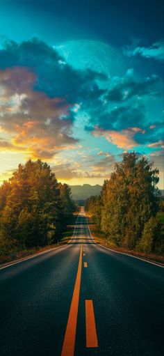 an empty road with trees on both sides and the sun setting in the distance behind it