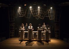 five people sitting at a table in the middle of a dark room with lights on