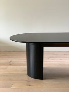 an oval black table sitting on top of a hard wood floor