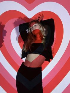 a woman is posing in front of a heart