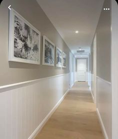 a long hallway with pictures on the wall and wood flooring in front of it