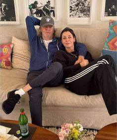 a man and woman sitting on top of a couch next to each other in a living room