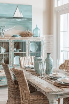 a dining room table with wicker chairs and blue vases on top of it