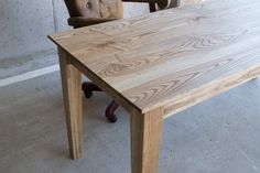 a wooden table sitting next to a brown chair in an empty room with concrete flooring