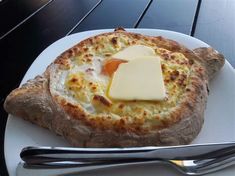 a white plate topped with an egg and cheese pizza