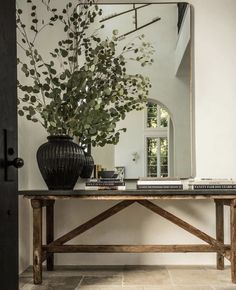 a table with a mirror, vase and books on it in front of a door