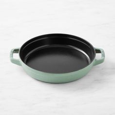 a green cast iron skillet sitting on a white counter