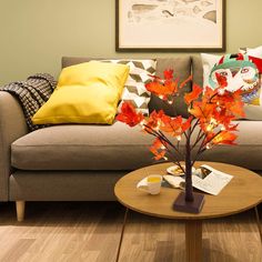 a living room with a couch, coffee table and fall leaves on the tree branch