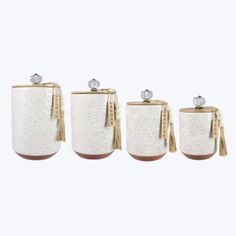 three white canisters with tasselled handles