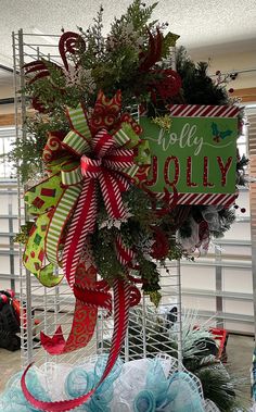 a christmas wreath is hanging on the side of a sign that says holly jollyy