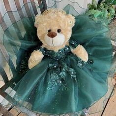 a teddy bear in a green dress sitting on a chair