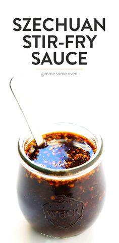 a jar filled with sauce sitting on top of a white table next to a spoon