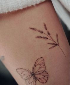 a small butterfly and flower tattoo on the side of a woman's stomach,