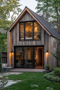 a small wooden house in the middle of a yard with grass and trees around it