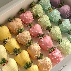 a box filled with lots of different colored chocolate covered strawberries next to each other