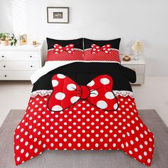 a bed with red and white polka dots on it, topped with a large bow